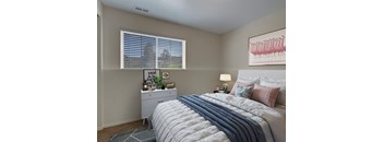 A bedroom with a bed, nightstand, and a window with blinds.