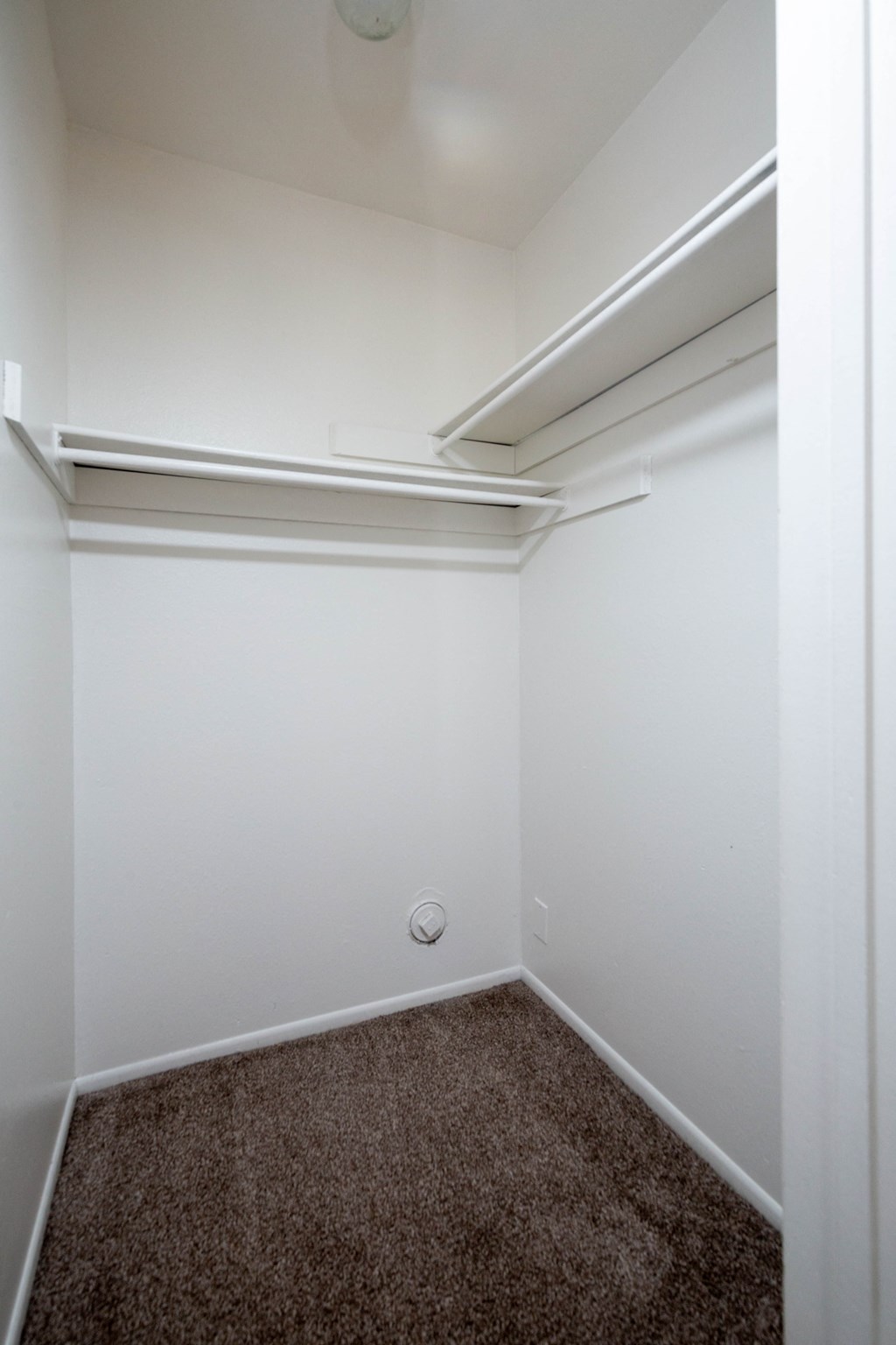 an empty room with a carpet and white walls
