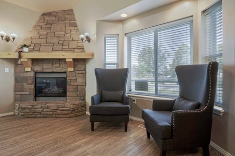 A living room with a stone fireplace and two leather chairs.