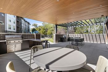 A patio with a table and chairs is covered by a wooden roof.
