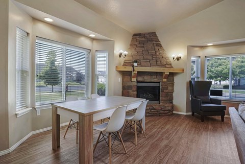A dining room with a stone fireplace and a table set for four.