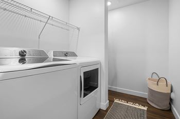 A laundry room with a washer and dryer and a basket on the floor.