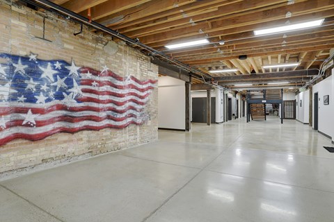 A large American flag painted on a brick wall in a spacious room.