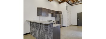 A kitchen with a white counter top and a black and white patterned backsplash.