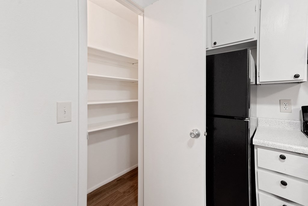 a kitchen with white cabinetry and a black refrigerator