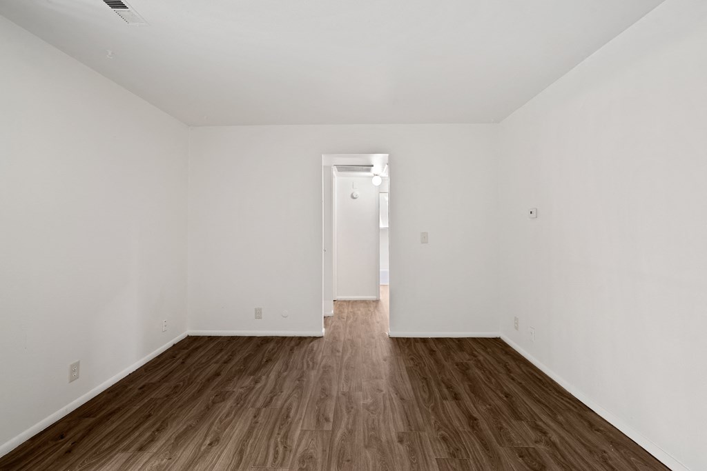 a bedroom with hardwood floors and white walls