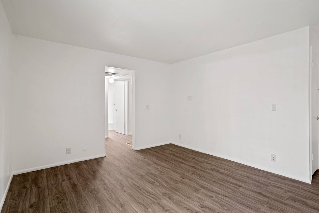 a bedroom with hardwood floors and white walls