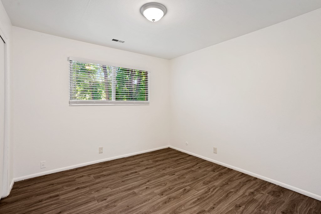 a bedroom with hardwood floors and white walls