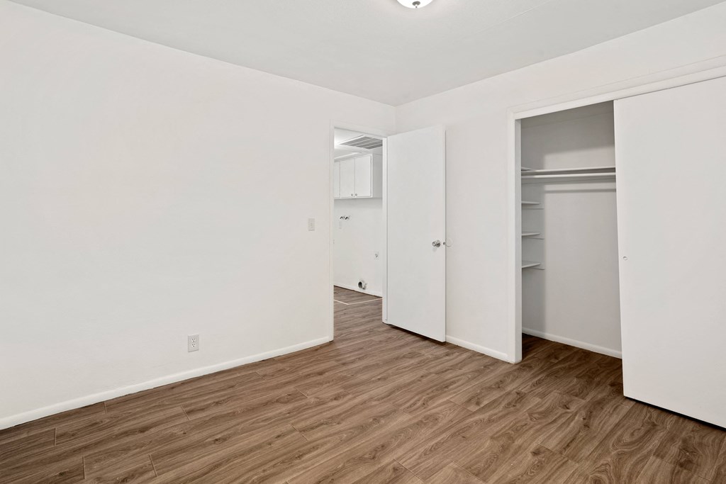 a bedroom with white walls and hardwood floors