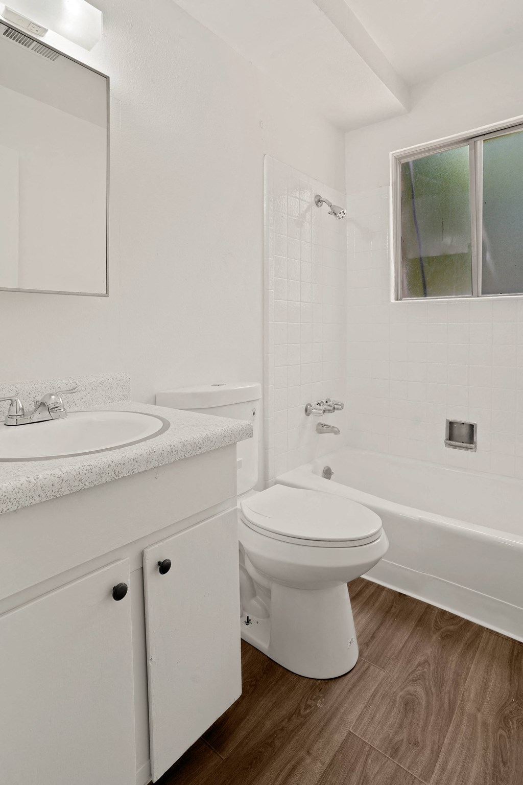 a bathroom with white fixtures and a wooden floor