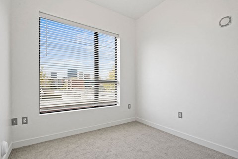an empty room with a large window with blinds