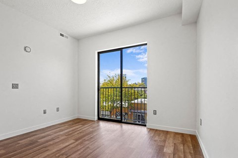 an empty living room with a sliding glass door to a balcony