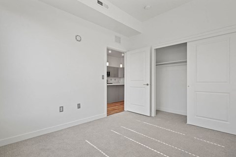 a bedroom with a closet and a door to a kitchen