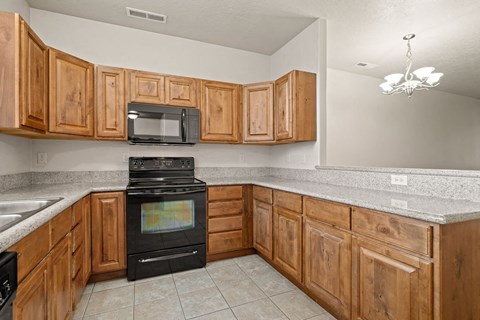A kitchen with wooden cabinets and a black stove top oven.