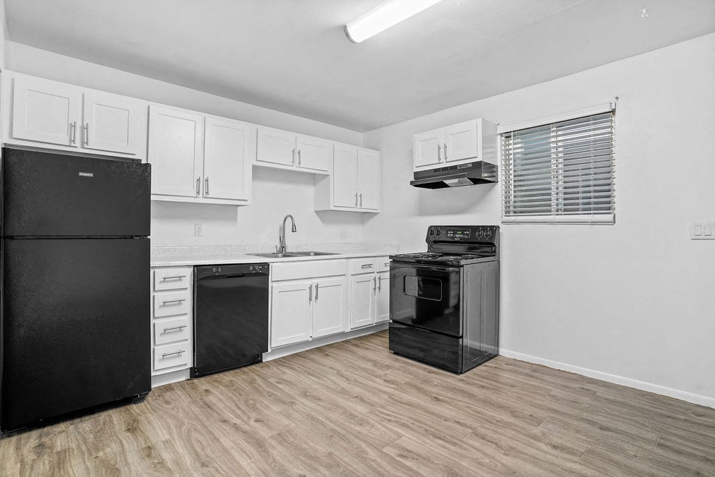 a kitchen with white cabinets and black appliances