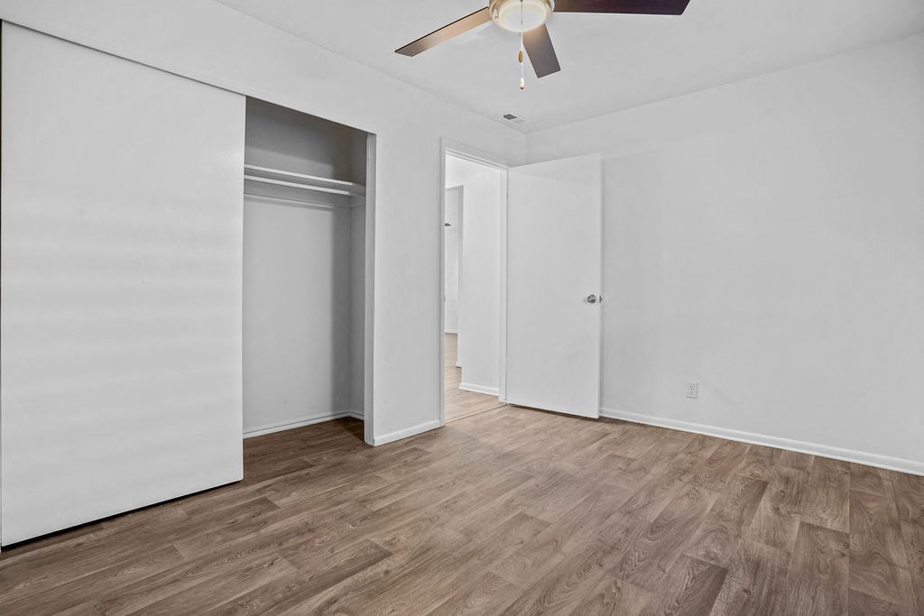 a living room with white walls and wood flooring and a ceiling fan