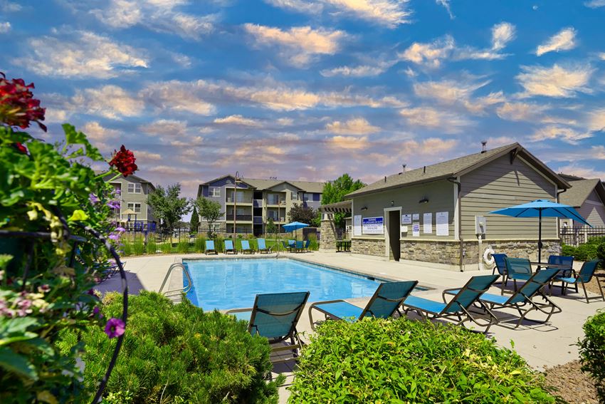 a swimming pool with chaise lounge chairs and umbrellas in front of a building