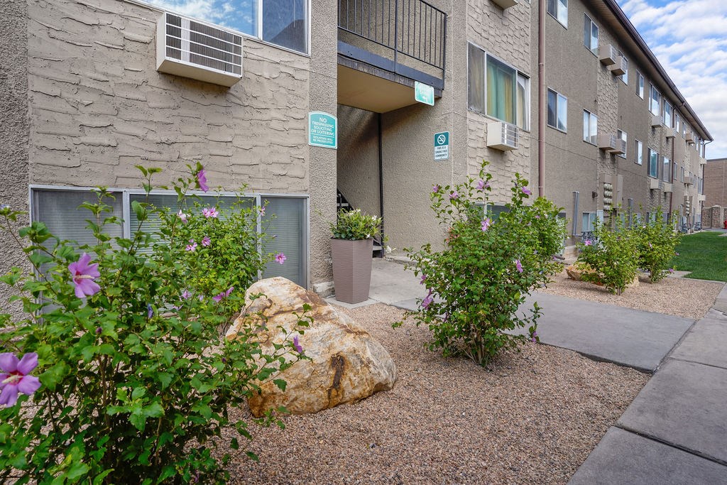 an outside view of a building with flowers and a rock