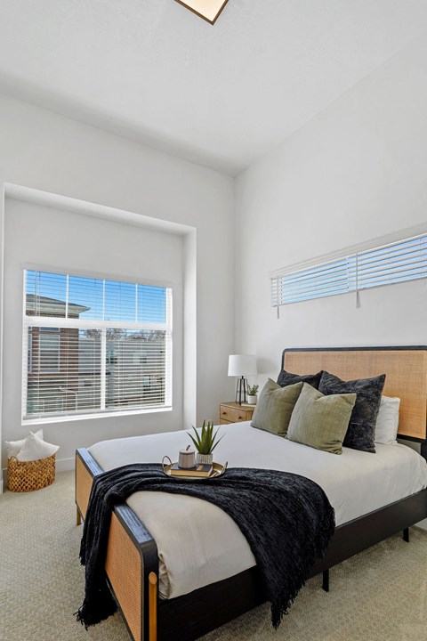 Modern bedroom with rattan bed frame and vaulted ceiling at Current by Lotus Apartments, Ogden, 84401