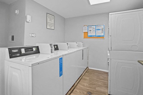 A laundry room with washers and dryers and a sign on the wall.