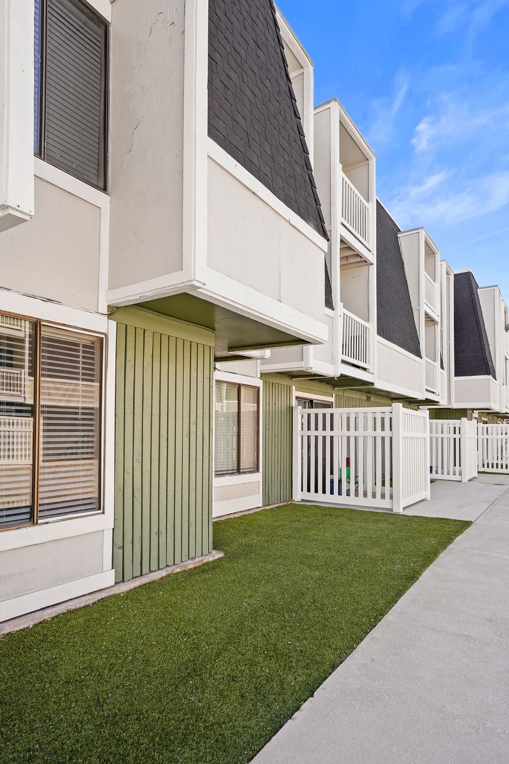 an exterior view of a row of apartments with grass and a sidewalk