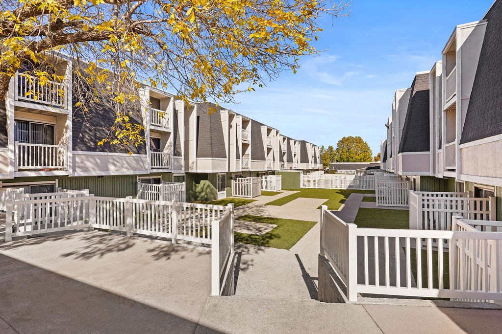 a row of apartments with white fences and lawns