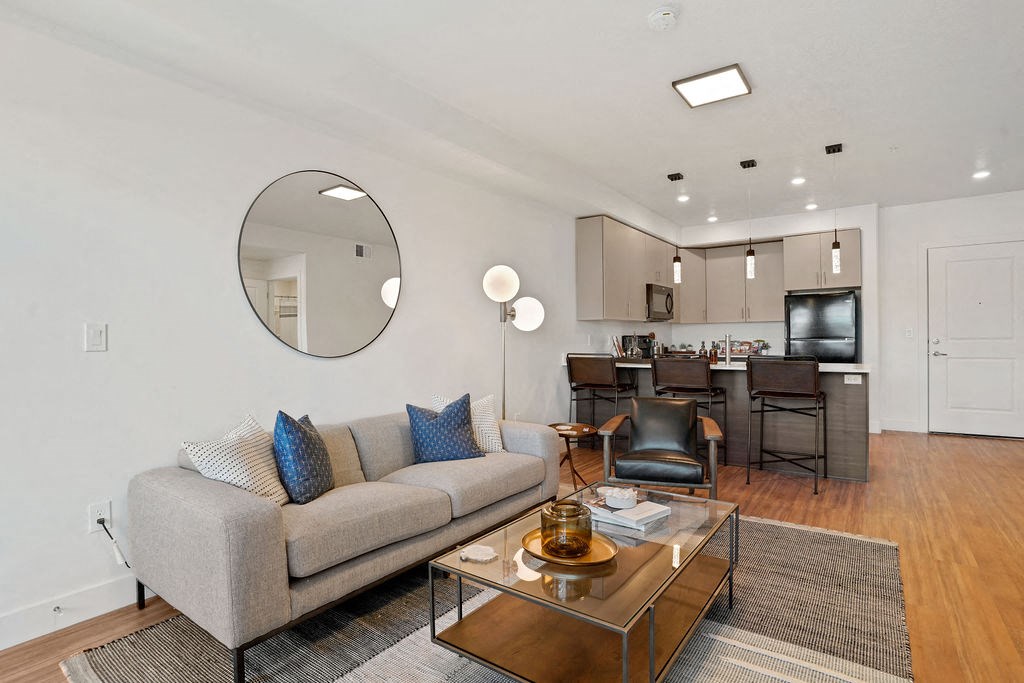 a living area with a couch coffee table and a kitchen in the background