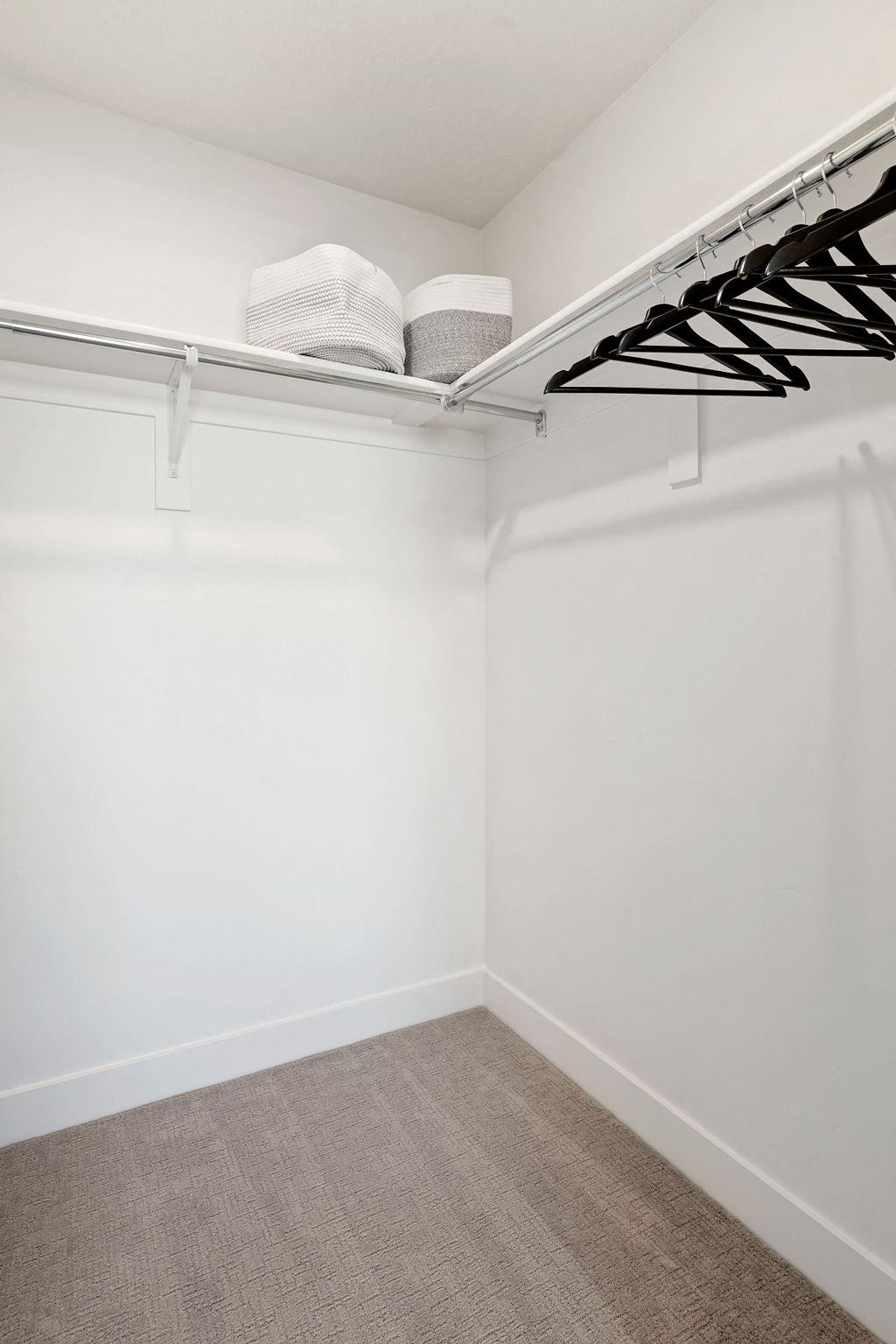 a walk in closet with white walls and a white shelf with a book on top of it