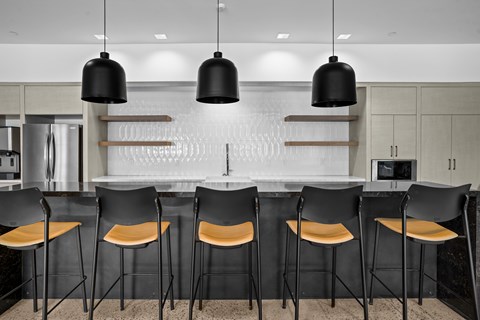 A modern kitchen with black chairs and a white backsplash.