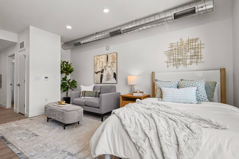 A bedroom with a large bed and a grey couch.
