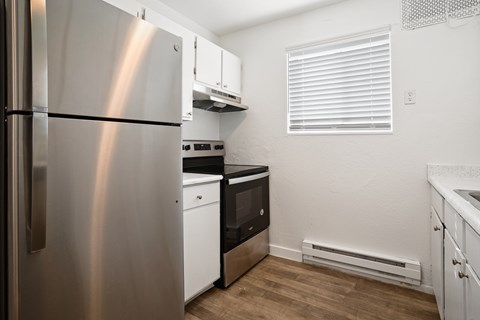 A kitchen with a stainless steel refrigerator and white cabinets.
