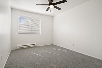A room with a ceiling fan and a window with blinds.