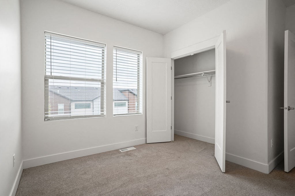 a bedroom with two windows and a closet