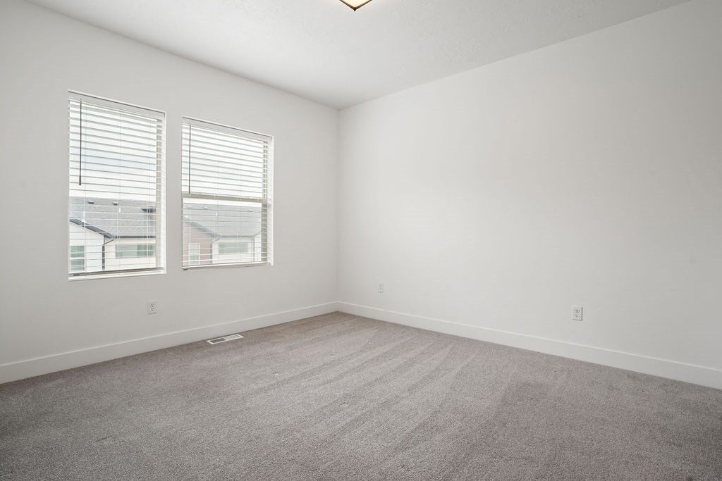 an empty room with two windows and a carpeted floor