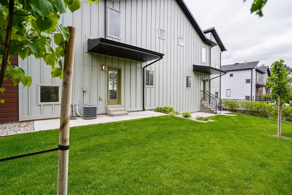 the front of a white house with green grass and a yard