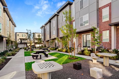 Outdoor courtyard with game tables and green space at Greens by Lotus Townhomes Apartments, Utah, 84403