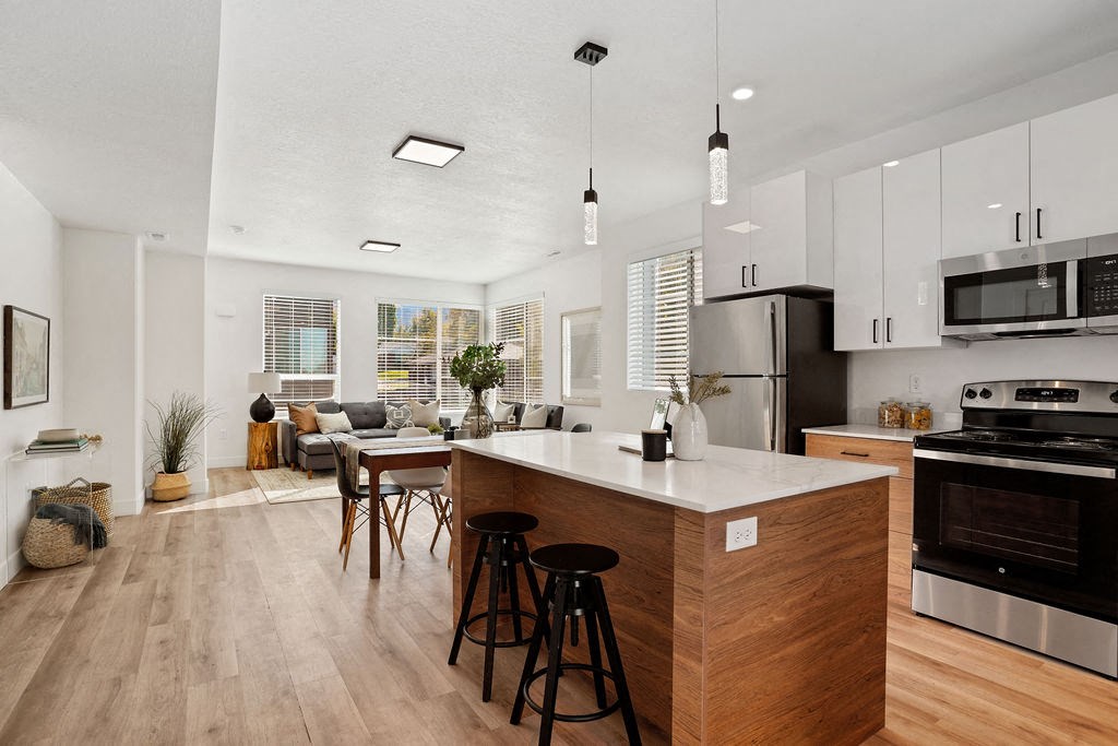 an open kitchen and living room with an island and stools
