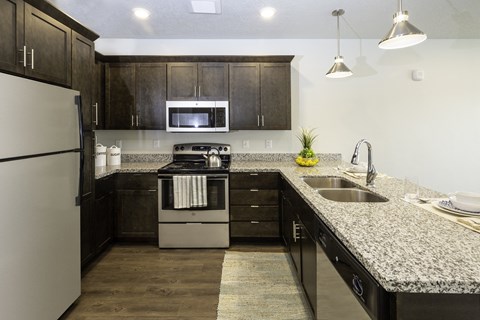 A modern kitchen with dark wood cabinets and granite countertops.