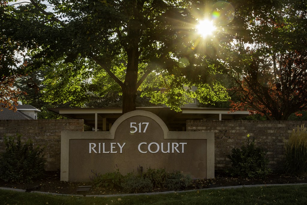 A sign that says Riley Court in front of a tree.