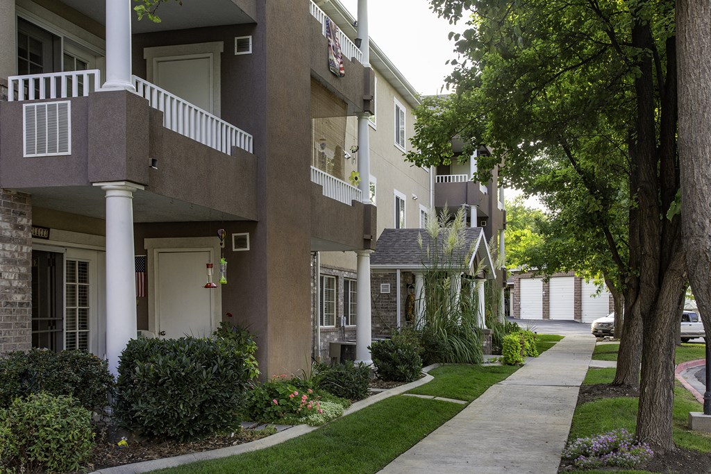 A row of apartment buildings with green trees in front.