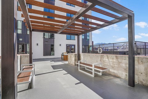 A patio with a wooden pergola and benches.
