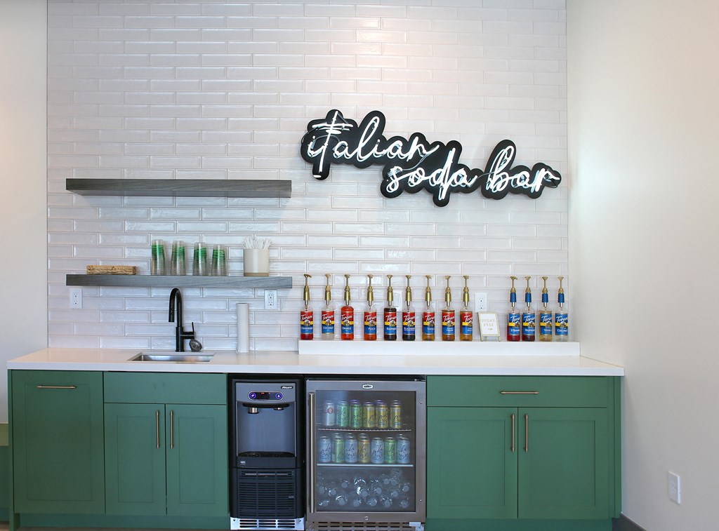 a bar with green cabinets and a white counter top with bottles of drinks