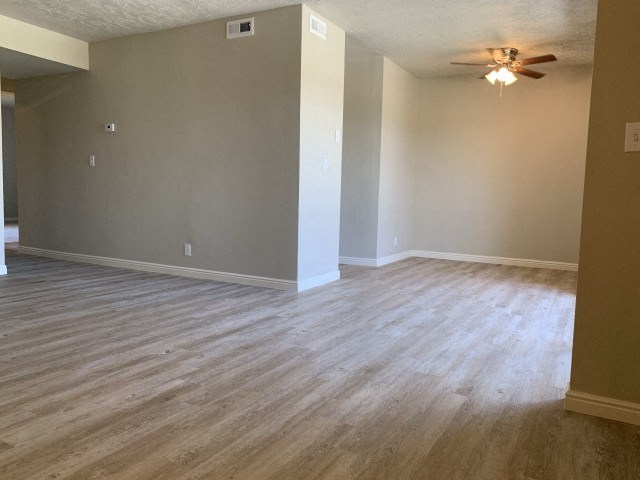 an empty living room with wood floors and a ceiling fan