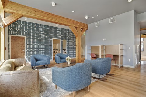 A living room with a blue sofa and a wooden beam ceiling.