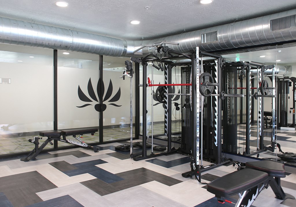 a workout room with weights machines and a logo on the wall