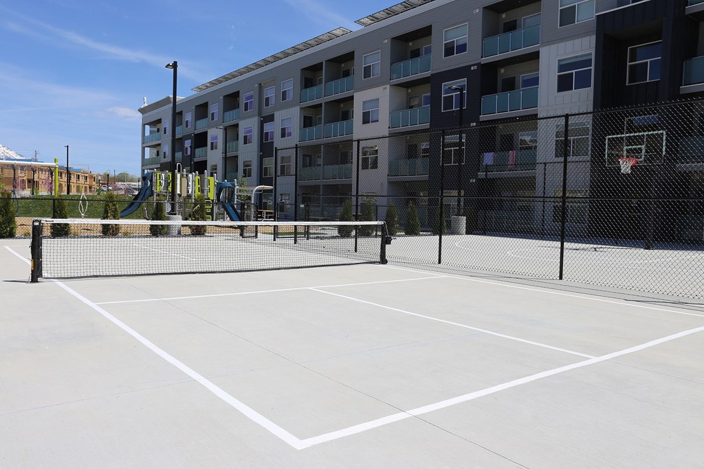 an outdoor tennis court with an apartment building in the background