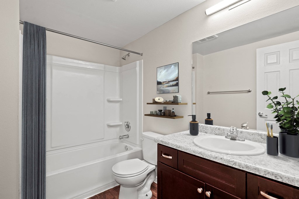 a bathroom with a toilet sink and shower and a mirror