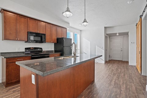 A kitchen with a black refrigerator and a black stove top oven.