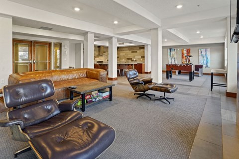 A living room with a brown leather chair and a brown leather couch.