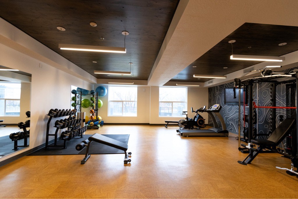 A gym with a variety of equipment including treadmills, weights, and exercise machines.